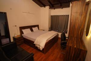 a bedroom with a bed and a chair and a television at Himalayanblues cottages&stays in Mukteswar +18 photos