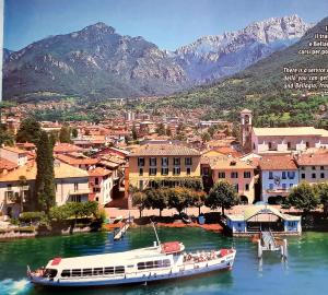 a boat is docked on a river with mountains in the background at L'AIRONE - casa vacanza in Mandello del Lario