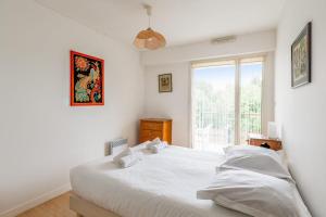 ein weißes Schlafzimmer mit einem Bett und einem Fenster in der Unterkunft Appartement Georges - Welkeys in La Rochelle