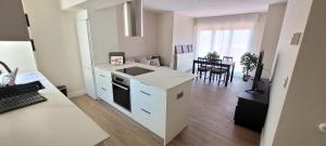 a kitchen with white cabinets and a dining room at SANNIKO APARTMENT Ático con Terraza in Getxo