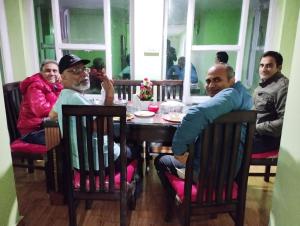Un groupe de personnes assises autour d'une table dans l'établissement THE BLISS HOME STAY, à Kalpa
