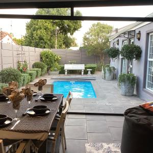 a patio with a table and a swimming pool at Villa Lyrique in Cape Town