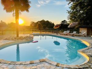 a large swimming pool with a sunset in the background at La Vigne d'Or B&B in Teuillac