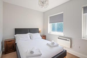 a bedroom with a bed with two towels on it at Weatherhead Lodge - Modern and Sleek Derby Apartment in Derby
