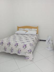 1 dormitorio con cama con colcha y almohadas de flores en Pousada Oliveiras, en Tobias Barreto