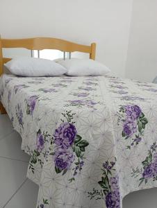 Una cama con un edredón púrpura y blanco. en Pousada Oliveiras, en Tobias Barreto