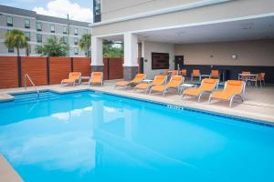 una piscina con sillas naranjas y una mesa en Holiday Inn Pensacola - University Area, an IHG Hotel en Pensacola