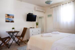1 dormitorio blanco con 1 cama y TV en רגע ערבה, en ‘En Yahav