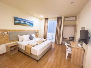 ein Hotelzimmer mit einem Bett, einem Schreibtisch und einem TV in der Unterkunft Rehendhi Villa in Maafushi