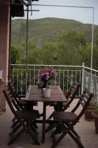 a wooden table with chairs and flowers on a porch at Countryside Cottage with Garden & Lake View in Peraía