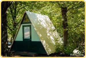 a green and white house with a triangular roof at Camping Federico Farm in Pontremoli