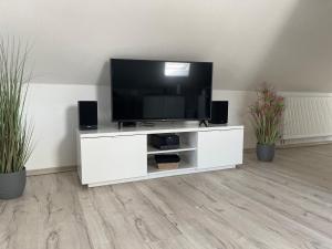 a white entertainment center with a flat screen tv on it at Moderne Ferienwohnung in Spaden / Wasserski / Badesee in Schiffdorf