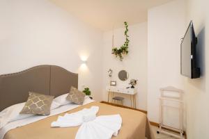 Schlafzimmer mit einem Bett mit weißer Bettwäsche und einem TV in der Unterkunft Vitti's Home Verona 3 in Verona