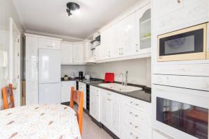 cocina blanca con armarios blancos y mesa en Los Baifos, en Puerto del Rosario