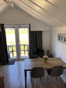 a dining room with a wooden table and chairs at Knus appartement met zicht op zeepolder in De Haan