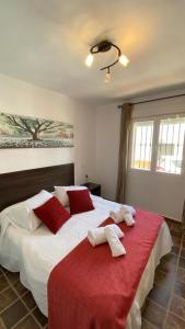 een slaapkamer met een groot bed met rode en witte kussens bij Casa en El Patras, Almonaster la Real in Patrás