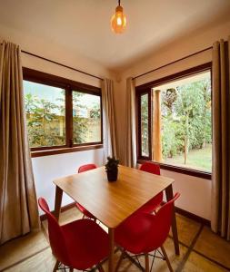 a dining room with a wooden table and red chairs at Maui Suítes e Chalés in Arraial d'Ajuda