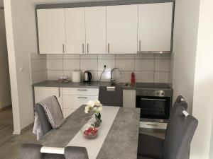 a kitchen with white cabinets and a table with flowers on it at Apartment Doris in Tomislavgrad