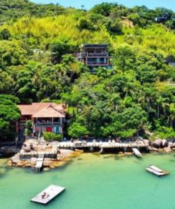 a resort with two boats in the water at Tainha da Praia Aparthotel in Bombinhas