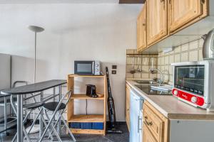 a small kitchen with a table and a microwave at Appartement Bréguières - Welkeys in Antibes