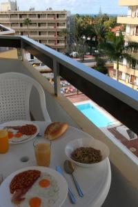 a table with breakfast food on a balcony with a pool at Playa del Ingles D&M near Yumbo in San Bartolomé