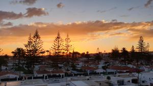 una puesta de sol sobre una ciudad con casas y árboles en Playa del Ingles D&M near Yumbo en San Bartolomé