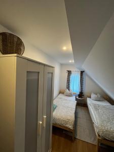 a attic room with two beds and a cabinet at Holiday house Vukelic in Mrkopalj