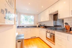 uma cozinha com armários brancos e uma janela em Spacious 1 Bedroom Apartment in Vibrant Angel em Londres