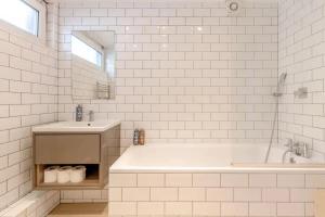 a white bathroom with a tub and a sink at Spacious 1 Bedroom Apartment in Vibrant Angel in London