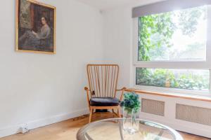 a room with a glass table and a chair and a painting at Spacious 1 Bedroom Apartment in Vibrant Angel in London