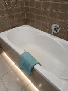 una vasca da bagno bianca con un asciugamano blu di Apartament Lux a Koszalin