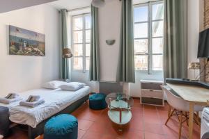 a bedroom with a bed and a desk and windows at Superb apartment located on the main square - Toulouse - Welkeys in Toulouse