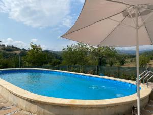 a large swimming pool with an umbrella at Sun Sonia casa in Sarnano
