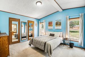 a blue bedroom with a bed and some windows at Rocky Mountain Rustic in Colorado Springs