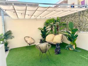 patio z 2 krzesłami, stołem i trawą w obiekcie CASA SOLE - Apartamento Playa San Juan NR. 4 w mieście Guía de Isora