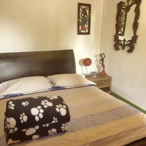 a bedroom with a bed with a black and white blanket at Hostal Estrella de Agua in Salento