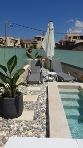 einem Pool mit Stühlen und einem Sonnenschirm auf einem Gebäude in der Unterkunft Zefyros Suite , Seafront retreat ! in Panormos