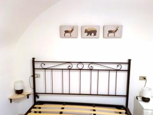 ein Schlafzimmer mit einem schwarzen Bett mit drei Bildern von Tieren an der Wand in der Unterkunft La Cameretta in Barisciano