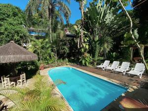 a swimming pool in a resort with chairs and a umbrella at Pousada Recanto das Estrelas in Abraão