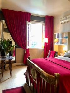 1 dormitorio con 1 cama con cortinas rojas y ventana en La Morada de Vicente López en Vicente López