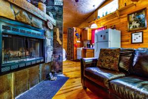 a living room with a leather couch and a fireplace at Panther Creek Cabins in Cherokee