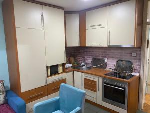 a kitchen with white cabinets and a blue chair at A First class za 4 osobe 2 spavaće sobe in Tuzla