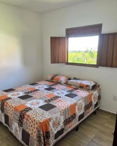 um quarto com uma cama com uma colcha em Chalés Samambaia em Bananeiras