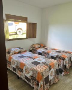 two twin beds in a room with a window at Chalés Samambaia in Bananeiras