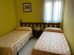a room with two beds and a window with a window at Apartamento economico a 100m de la playa ESTANCIA MINIMA 4 NOCHES in A Pobra do Caramiñal