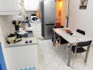 a kitchen with a table and a refrigerator at HOUSE 3Bedroom Maisonette ΕΞΟΧΙΚΟ Alyki PAROS 50m from BEACH ideal for families in Aliki