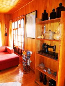 Zimmer mit Holzwänden, einem roten Sofa und einem Regal in der Unterkunft Hostal Torre de Babel in Castro
