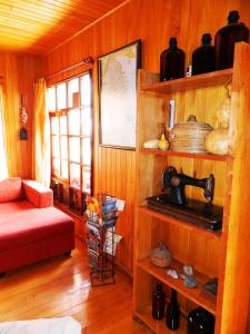 Habitación con paredes de madera, sofá rojo y estante. en Hostal Torre de Babel, en Castro