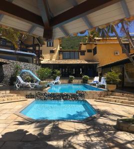 uma piscina com duas cadeiras e um edifício em Nautillus Pousada em Arraial do Cabo