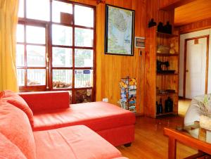 a living room with a red couch and windows at Hostal Torre de Babel in Castro